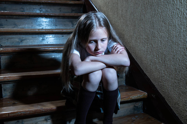 Verdrietig, depressief, ongelukkig schoolmeisje lijden pesten en misbruik eenzaam en hopeloos zittend op trap met donkere licht gevoel. School isolatie, pesterijen, intimidatie en misbruik concept - Foto, afbeelding