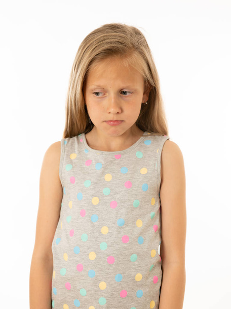Portrait of a pretty bullied, depressed, alone, tired, stressed young child looking unhappy and sad. Isolated withe background. Human emotions, facial expressions, body language and bulling - Foto, imagen