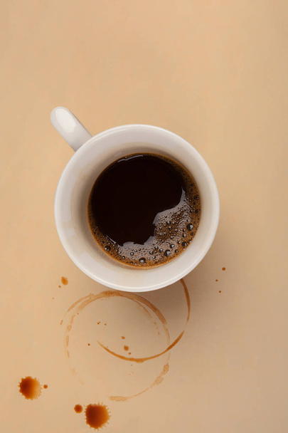 Cup of espresso with coffee stains on beige table from above. Working overtime. - Foto, afbeelding