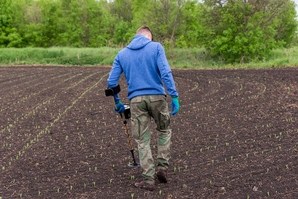 чоловік шукає скарби на землі з металошукачем, ходить полем, пищить золото
 - Фото, зображення