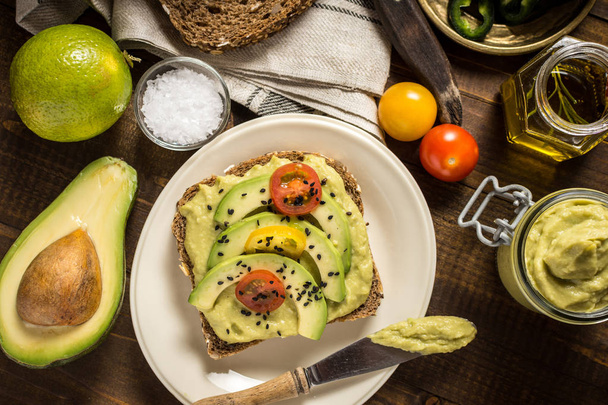 Avocadoaufstrich Guacamole und Scheiben mit frischen Kirschtomaten und schwarzem Sesam. Konzept für gesundes Frühstück. - Foto, Bild
