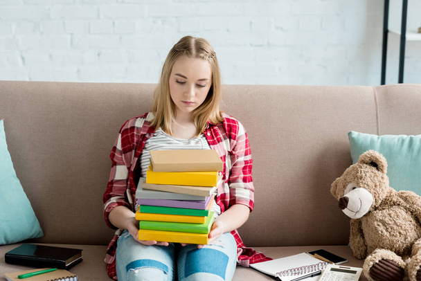 menina estudante adolescente com pilha de livros sentados no sofá
 - Foto, Imagem