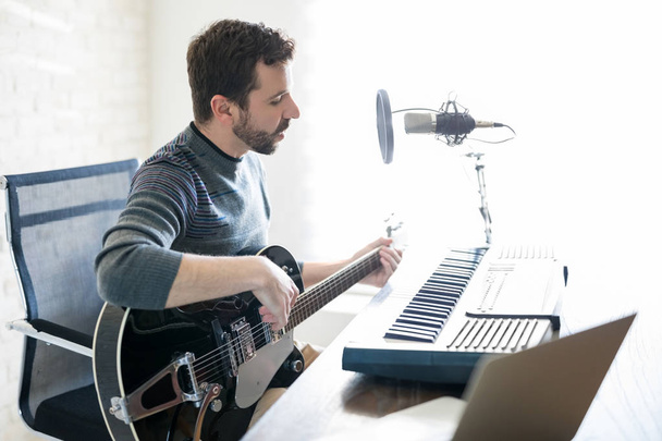 Profilbild eines gutaussehenden jungen Mannes, der in einem Radiosender sitzt, Gitarre spielt und in einer Live-Show Lieder singt - Foto, Bild