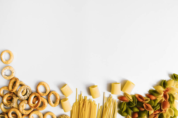 Background with different types of raw pasta and pretzels. Flatlay style, top view. Different carbs sources. Copy space, flat lay - Photo, image