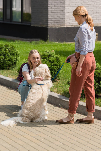 mother and daughter spending time together on street with their dog - Фото, зображення