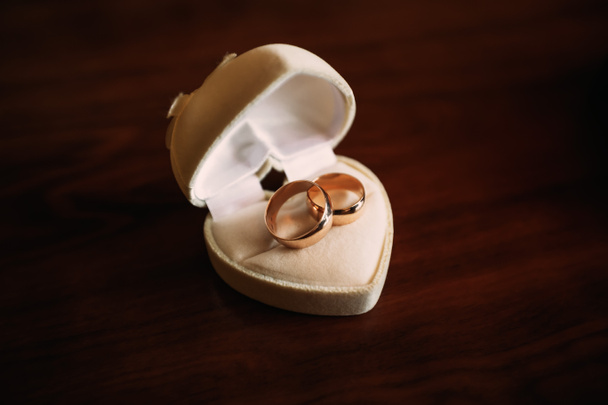 Primi piani di una scatola bianca a forma di cuore con anelli da sposa all'interno - Foto, immagini