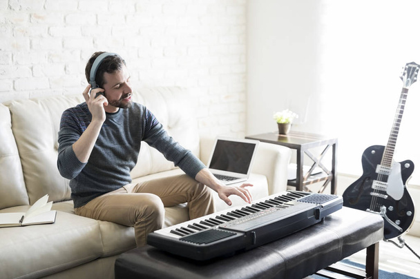 Hombre hispano en sus 30 años escuchando la melodía tocada en el piano eléctrico por él
. - Foto, imagen