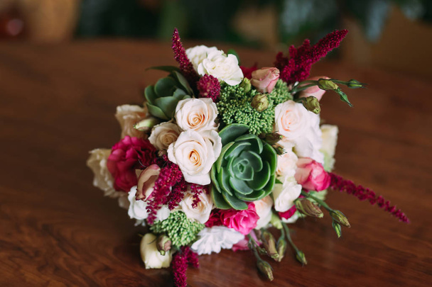 木製の表面に横たわるバラの美しく装飾された結婚式の花束 - 写真・画像