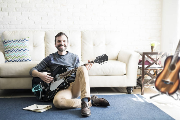 本とギターで床に座って笑顔の男性音楽作曲家 - 写真・画像
