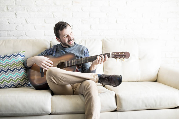 Attractive young hispanic man playing a guitar song at home - Fotoğraf, Görsel