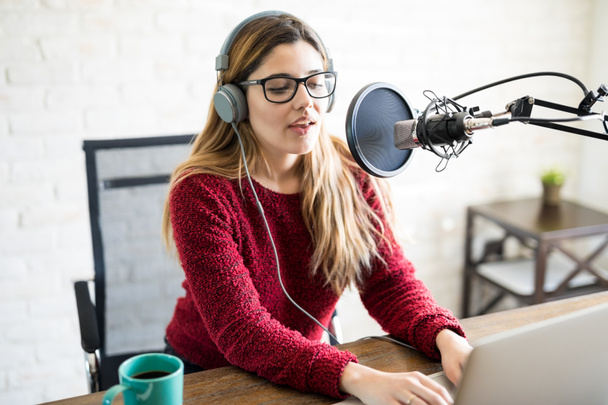 Portrait of attractive caucasian woman wearing headphones and talking at online radio station - Foto, afbeelding