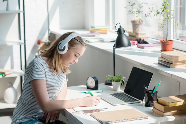 teen student girl listening music with headphones and doing homework - Foto, immagini
