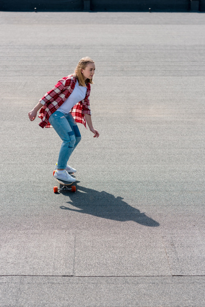 high angle view of active teen girl riding skateboard on rooftop - Φωτογραφία, εικόνα