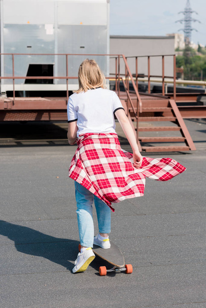 вид ззаду дівчини-підлітка, що їде скейтборд на даху
 - Фото, зображення