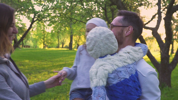 Rodzina szczęśliwy tulenie na trawie. Rodzice i ich dwie córki są obejmującego na trawniku park. Kwitnący Sad. - Materiał filmowy, wideo