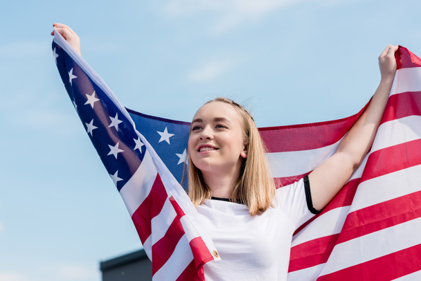 feliz chica adolescente con bandera de EE.UU. en frente del cielo azul
 - Foto, imagen