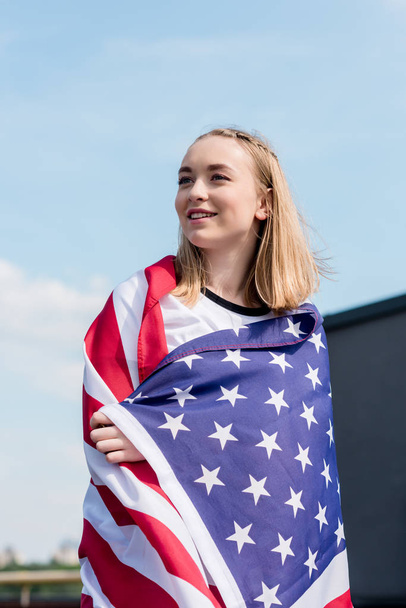 beautiful teen girl covered with usa flag in front of blue sky - 写真・画像