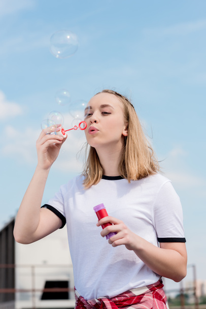 beautiful teen girl blowing soap bubbles in front of blue sky - Photo, Image