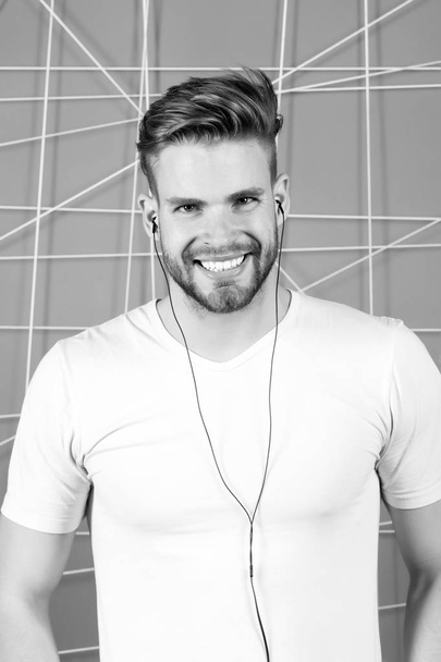 Bearded man enjoy listening music with earphones. Happy macho with audio headphone device. Media entertainment relaxation concept - Photo, image