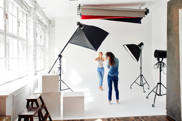 Girl photographer photographing the model in studio - Photo, Image