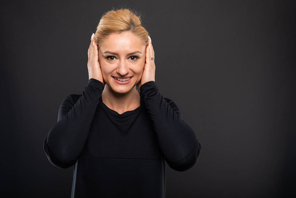 Retrato de bonita entrenadora de gimnasia cubriendo orejas como concepto sordo sobre fondo negro con área de publicidad de copypsace
 - Foto, imagen