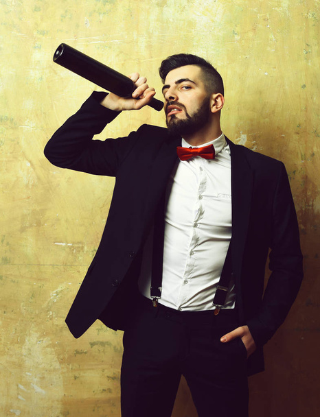 Man with beard in suit and red bow drinks wine - Фото, изображение