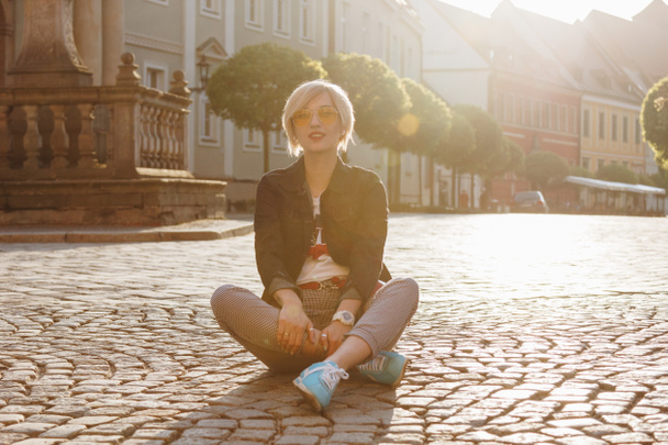 piękna młoda kobieta siedzi na bruku ulicy Wrocław, Polska - Zdjęcie, obraz