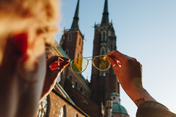 スタイリッシュなサングラスを押し、ヴロツワフの大聖堂見て女性のショットをトリミング - 写真・画像