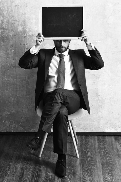 businessman or serious man holding a blackboard - Foto, Imagen