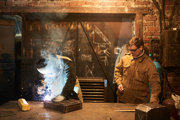 welders wearing coveralls working together at factory  - Foto, Imagem