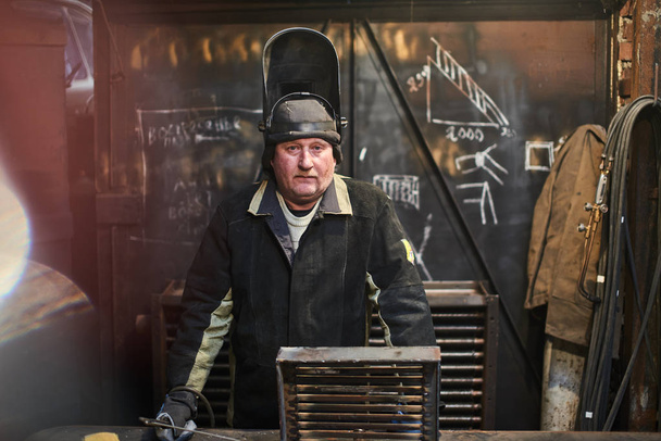 welder wearing safety equipment looking at camera while standing at factory  - Фото, зображення