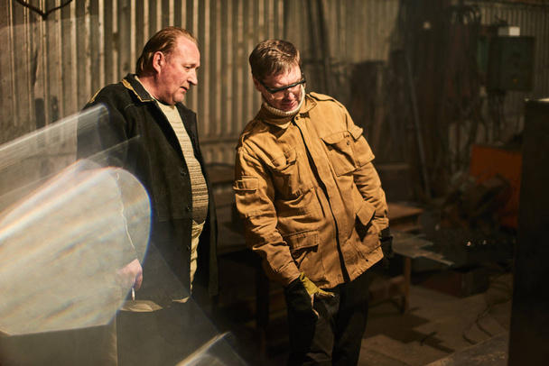 two welders relaxing after work while standing at factory  - Foto, immagini