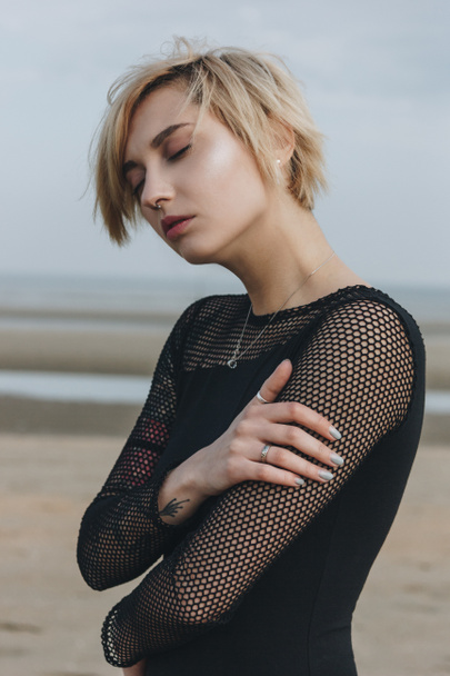 sensual young woman in black shirt in front of seashore on cloudy day - Photo, Image
