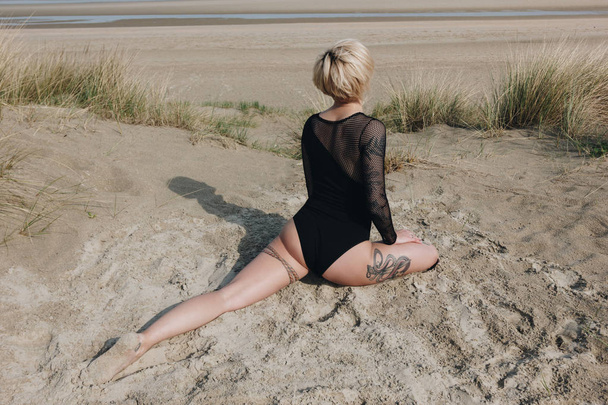fiatal nő Body gyakorló jóga a egy négylábú király galamb jelentenek a homokos dune - Fotó, kép