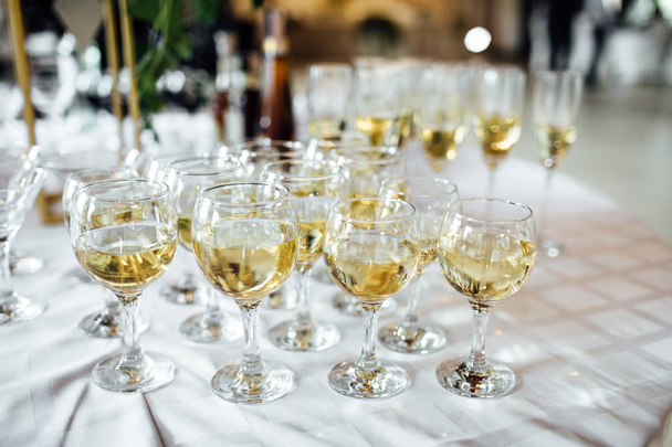 A lot of wine glasses with a cool delicious champagne or white wine at the bar. Alcohol background. - Photo, Image