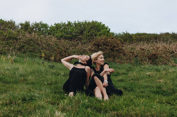 happy young women in black relaxing on green meadow - Valokuva, kuva