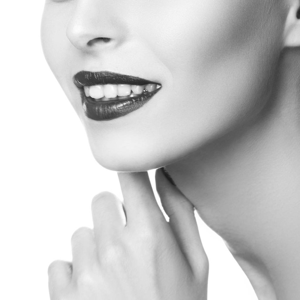 Частичный вид портрета улыбающейся женщины с темным макияжем губ
 - Фото, изображение