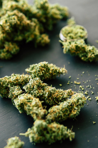 Macro van cannabis toppen marihuana met schubben en geplette onkruid op een zwarte tabel insta close-up - Foto, afbeelding