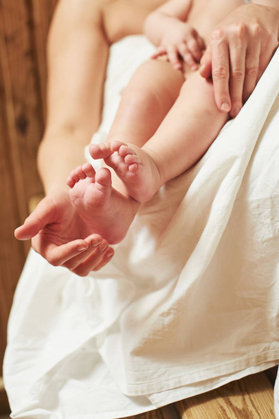 woman holding little baby while sitting in sauna - Foto, afbeelding