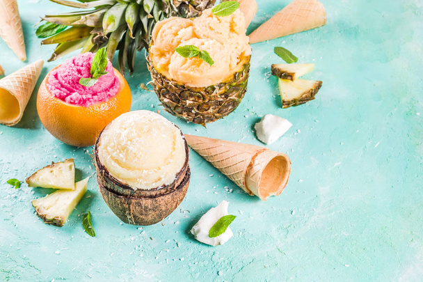 Summer holiday vacation concept, set various tropical ice cream sorbets, frozen juices in pineapple, grapefruit and coconut, light blue concrete background copy space - Фото, изображение