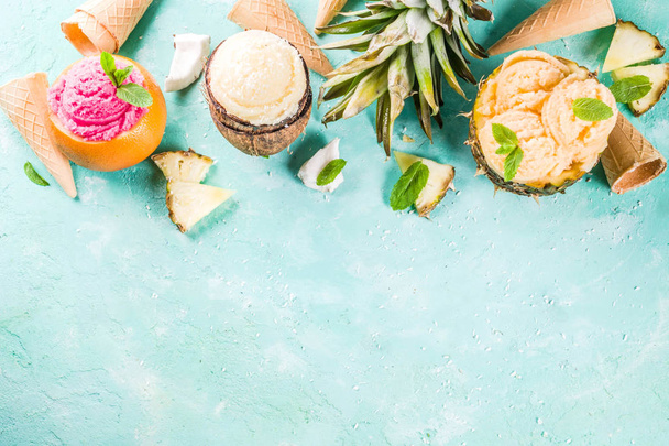 Summer holiday vacation concept, set various tropical ice cream sorbets, frozen juices in pineapple, grapefruit and coconut, light blue concrete background copy space - Foto, afbeelding