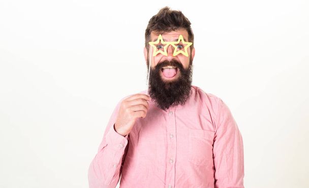Happy bearded man on white background, birthday fun concept. Man with long beard and open mouth wearing star shaped glasses. Hipster with excited look and trendy beard posing with party accessories - Fotó, kép