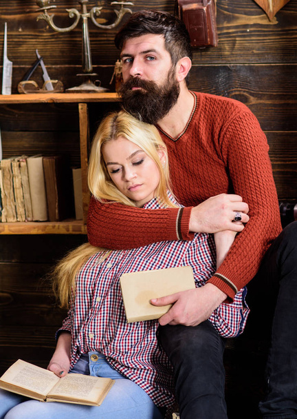 Romantic evening concept. Couple in wooden vintage interior enjoy poetry. Couple in love reading poetry in warm atmosphere. Lady and man with beard on dreamy faces hugs and reading romantic poetry - Fotoğraf, Görsel