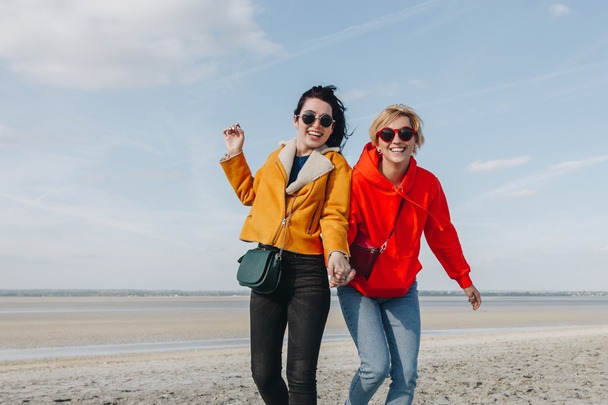 smiling female friends on sandy beach, Saint michaels mount, Normandy, France - 写真・画像