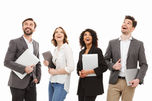 Portrait of a group of happy multiracial business people holding laptop computers and looking up isolated over white background - Valokuva, kuva