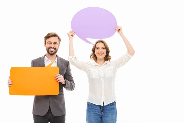 Portrait of a happy young business couple holding empty speech bubbles isolated over white background - Fotografie, Obrázek