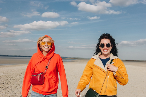 onnellisia tyttöjä kävelemässä hiekkarannalla, Saint Michael mount, Normandy, Ranska
 - Valokuva, kuva