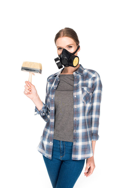 jonge vrouw in gasmasker holding kwast geïsoleerd op witte achtergrond  - Foto, afbeelding
