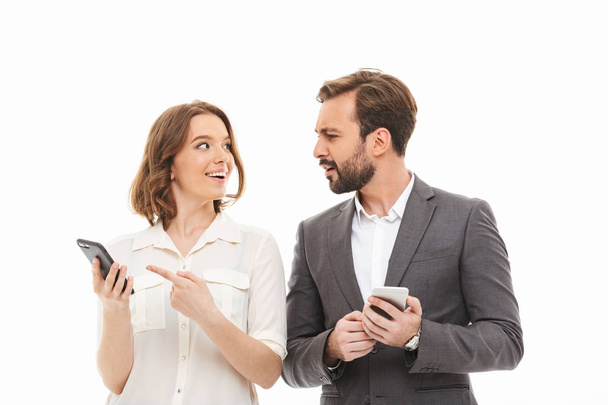 Muotokuva hymyilevästä liikepariskunnasta, jolla on matkapuhelimet ja joka puhuu erillään valkoisella taustalla
 - Valokuva, kuva