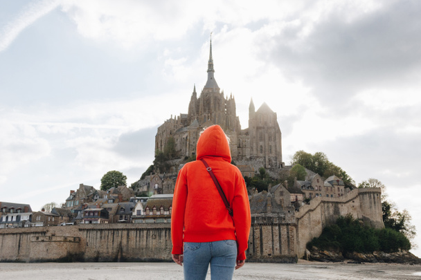 vue arrière de fille en rouge regardant le mont Saint michaels en Normandie, France
 - Photo, image